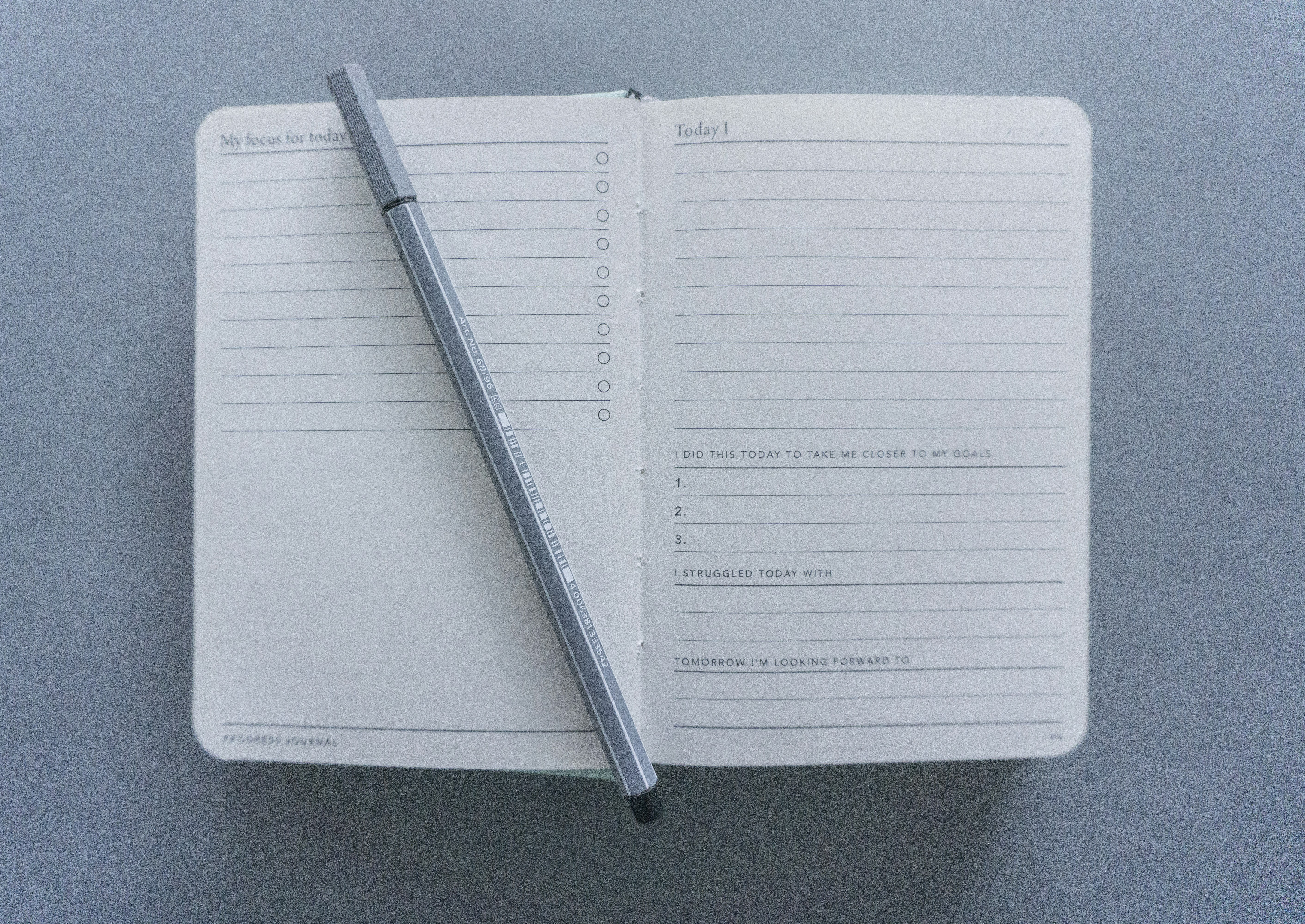 Office supplies including a writing implement and ring binder with a progress journal page displaying the text "My focus for today".